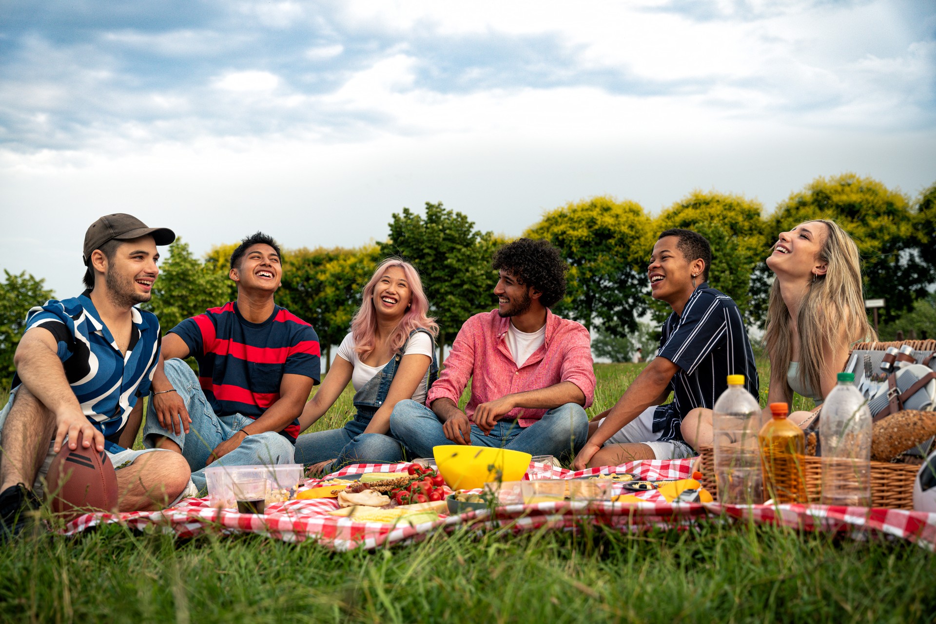 Group of multiethnic teenagers spending time outdoor on a picnic at the park