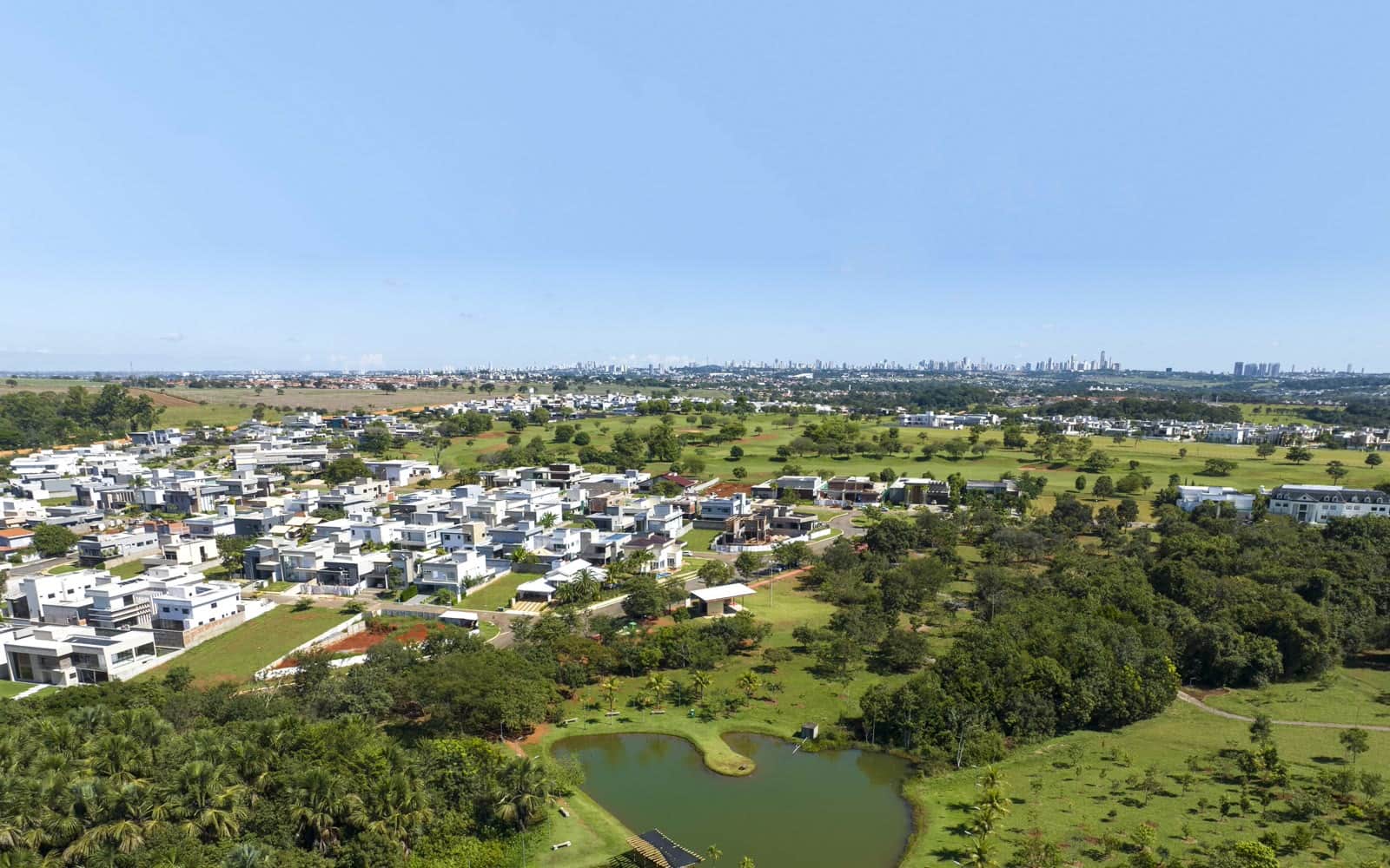 Casas construídas em condomínio fechado dentro de Goiânia, com a cidade ao fundo
